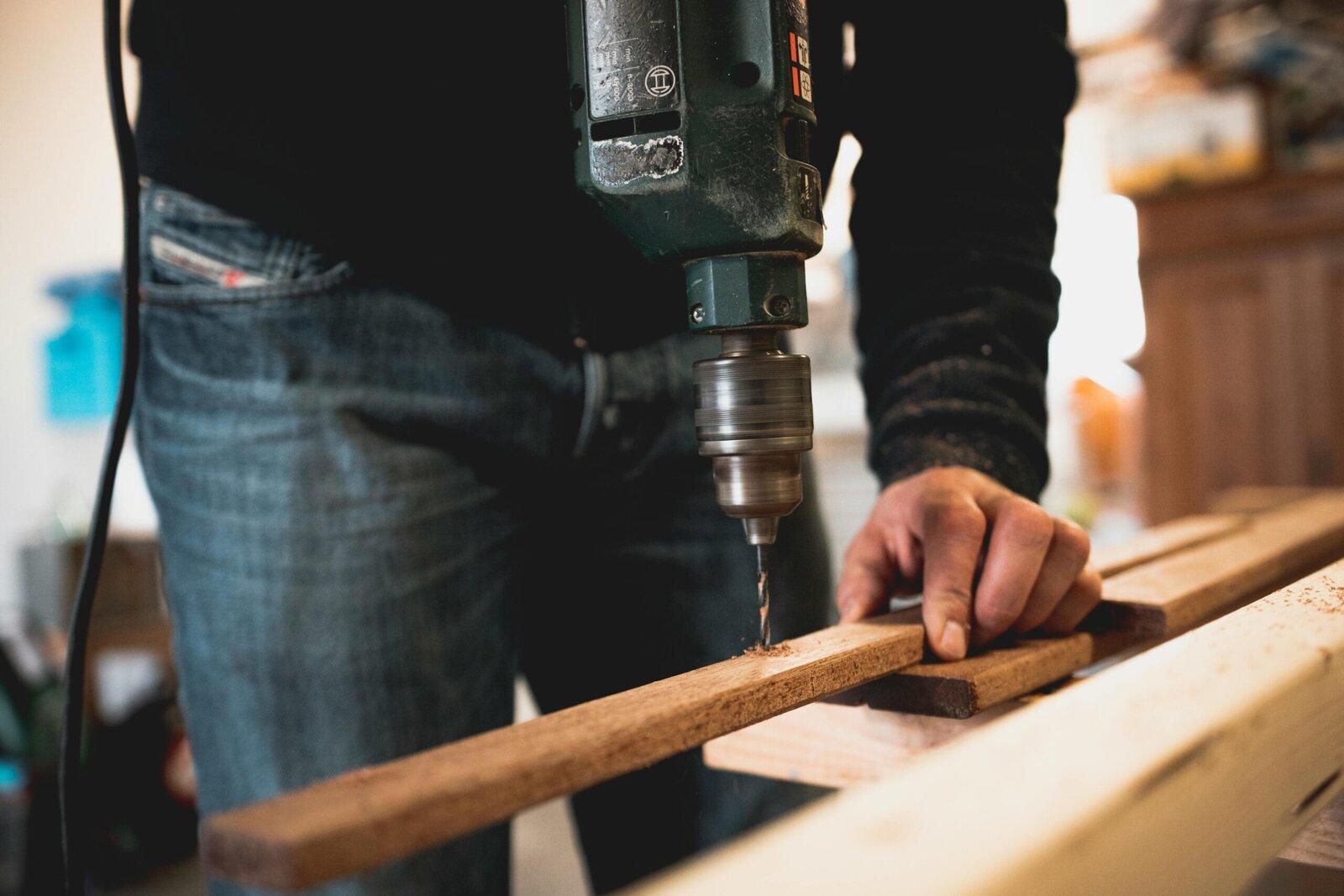 Close-up of a carpenter carefully drilling a piece of wood trim